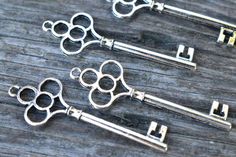 three antique style keys sitting on top of a wooden table