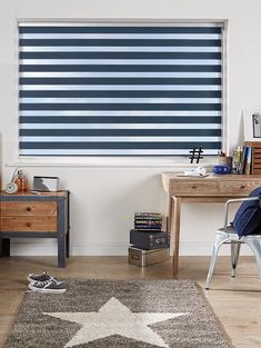 a room with a desk, chair and window covered in blue roller shades on the wall