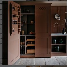 an open cabinet in the middle of a room with shelves and vases on it