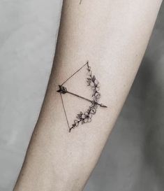 an arrow tattoo on the arm with flowers and leaves around it, as well as a bow