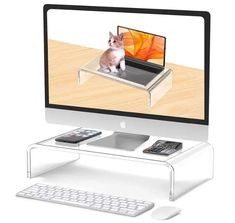 a computer screen with a cat sitting on top of it, next to a keyboard and mouse