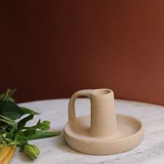 a white vase sitting on top of a marble table next to green leaves and flowers