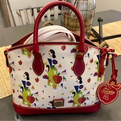 Celebrate Disney's Snow White 85th Anniversary With This Elegant Dooney & Bourke Satchel. Featuring A Whimsical Print Of Snow White And Her Friends, The Bag Is Crafted From Coated Cotton With Genuine Leather Trims. It Includes A Zip-Top Closure, Three Interior Slip Pockets, An Interior Zip Pocket, And A Key Hook. The Bag Also Has Leather Carry Handles, An Adjustable And Detachable Shoulder Strap, And A Commemorative Leather Apple Tag. Goldtone Hardware And Fabric Lining Complete The Design. Dime Dooney Bourke Handbags Disney, Apple Tag, Disney Purse, Dooney And Bourke Disney, Snow White And The Seven Dwarfs, The Seven Dwarfs, Key Hook, Seven Dwarfs, Dooney And Bourke