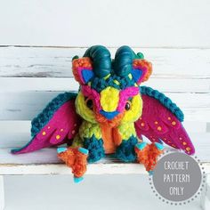 a colorful stuffed animal sitting on top of a white bench with its wings spread out