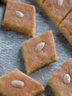 several pieces of cake sitting on top of a baking sheet with almonds in the middle