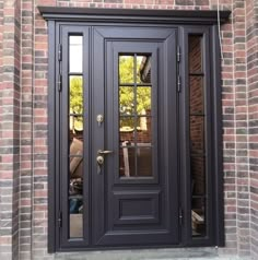 a black double door on a brick building with glass panes in the front and side