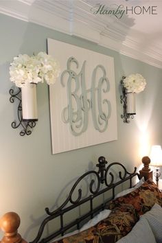 a bed room with a neatly made bed and two vases on the headboard