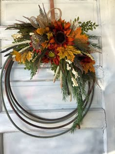 a wreath is hanging on the door with autumn flowers and leaves in front of it