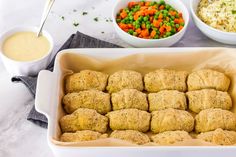 a pan filled with chicken nuggies next to bowls of rice and carrots