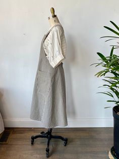 a dress on a mannequin next to a potted plant in a room