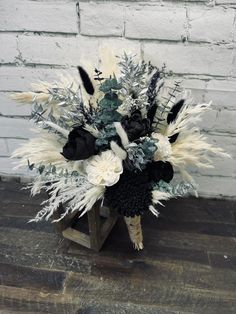 a bouquet with feathers and flowers on a wooden stand in front of a brick wall