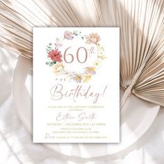 a birthday card with flowers and the number sixty on it, sitting next to a fan