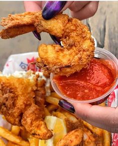 a person is holding some fried food in their hand and dipping sauce on the side