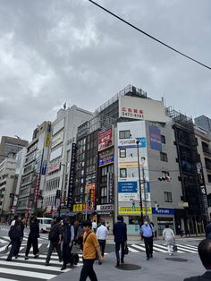 many people are crossing the street in front of buildings