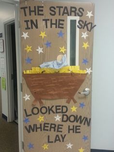 a door decorated to look like a baby in a manger with stars and the words, the stars in the sky looked down where he lay