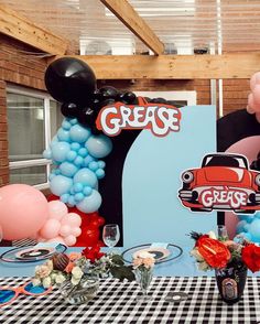 a table topped with balloons and decorations for a grease birthday party or baby's first birthday