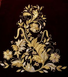 a gold embroidered design on a red velvet background with white and yellow flowers in the center