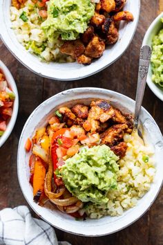 three bowls filled with different types of food on top of a wooden table next to silverware