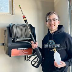 a man holding a spray bottle next to a large hose dispensing machine