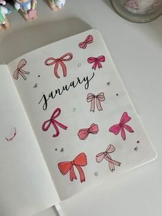 an open book with pink bows and the word january written on it in cursive writing