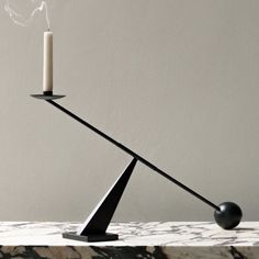 a black candle holder with two candles on it and a marble counter top in the background