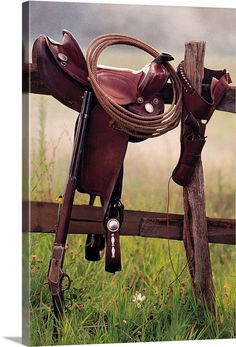 a horse saddle and reins hanging on a wooden fence