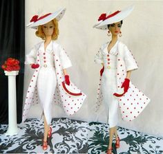 two dolls dressed in white and red with matching outfits, one is holding a flower