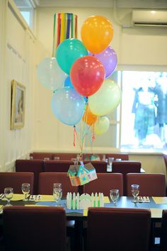 a bunch of balloons that are in the air over a table with place settings on it