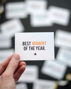 someone holding up a card with the words best moment of the year written on it