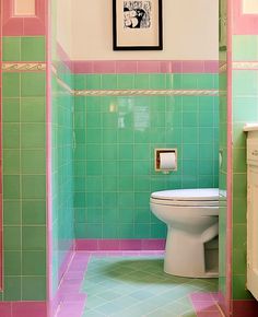 a bathroom with green and pink tiles on the walls, toilet and sink in it