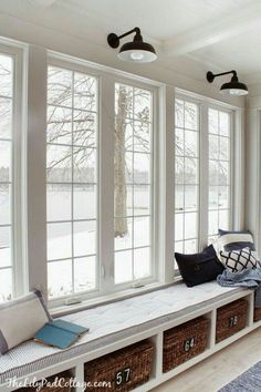 a window seat in the corner of a room with lots of windows and pillows on it