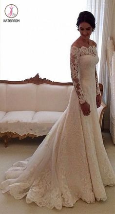 a woman in a white wedding dress standing next to a couch and looking at the camera