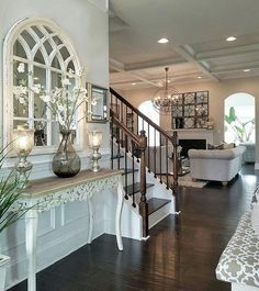 a living room filled with furniture and a fire place next to a stair case on top of a hard wood floor