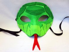 a green mask with red nose and black ribbon on it's side, sitting on a white surface