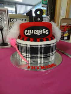 a birthday cake with the number eighteen on top and plaid pattern, sitting on a pink table cloth