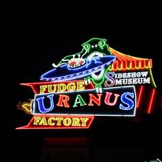 the neon sign for fudge and uranos factory is lit up at night