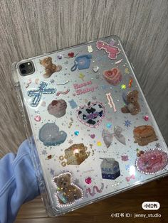 someone holding up a clear case with lots of stickers on it's side