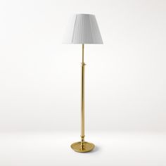 a floor lamp with a white shade on the base and a gold plated base