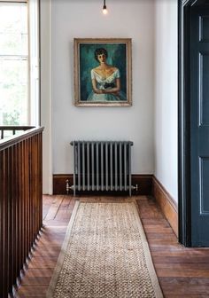 a painting hanging on the wall above a radiator in a room with wooden floors