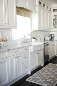 a kitchen with white cabinets and an area rug in front of the stove top oven