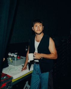 a man standing in front of a table holding a cup