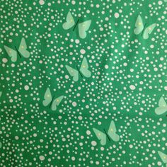 a green background with white polka dots and butterflies