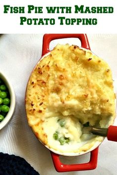 fish pie with mashed potato topping in a red casserole dish next to peas