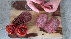 a person is cutting up some meat on a wooden board with flowers and wine glasses