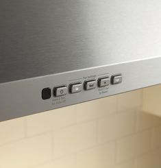 the bottom panel of a stainless steel range hood with knobs and buttons on it