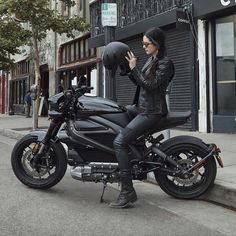 a woman sitting on top of a black motorcycle