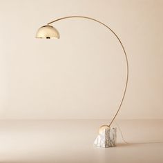 a floor lamp with a marble base and a gold light shade on the top of it