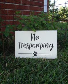 a sign that says no trespoping in front of a brick wall and green grass