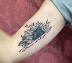 a sunflower tattoo on the arm with words written below it and an arrow in the middle