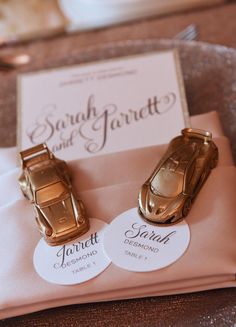 two gold cufflinks sitting on top of a pink napkin next to a card